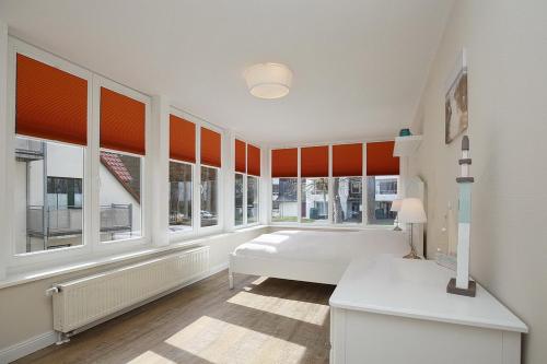 a bedroom with orange blinds and a bed and windows at Strandvilla Krabbe Wohnung 04 in Boltenhagen