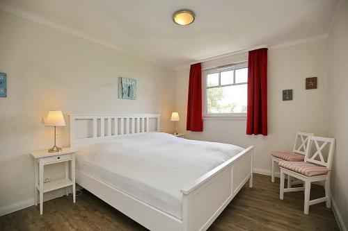 a bedroom with a large white bed and red curtains at Reethaus Am Mariannenweg 15b in Boltenhagen
