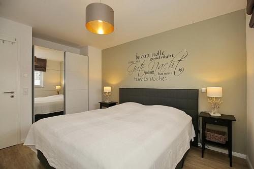 a bedroom with a white bed and a sign on the wall at Reethaus Am Mariannenweg 05b - Haus Baltic in Boltenhagen