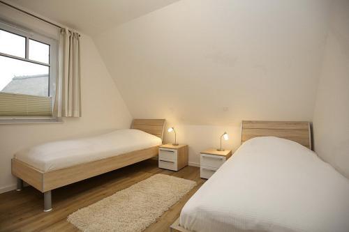 two beds in a room with two tables and a window at Reethaus Am Mariannenweg 17a in Boltenhagen