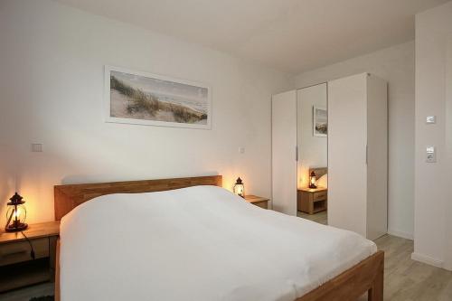 a bedroom with a white bed and two night stands at Reethaus Am Mariannenweg 13b in Boltenhagen