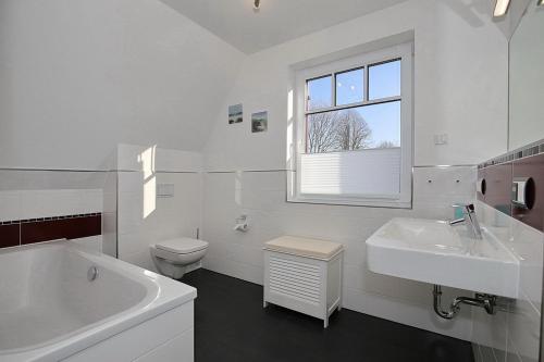 een witte badkamer met een bad, een wastafel en een toilet bij Reethaus Am Mariannenweg 13b in Boltenhagen