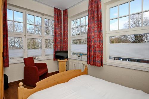 奥斯赛拜-屈隆斯博恩La Mer Wohnung 08的一间卧室，里面有一张床、一把椅子和几扇窗户。