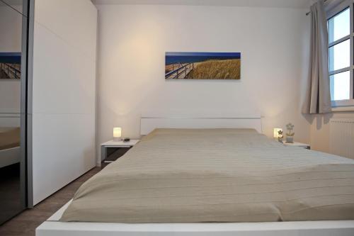 ハイリゲンダムにあるResidenz von Flotow Wohnung 18の白いベッドルーム(大型ベッド1台、テーブル2台付)