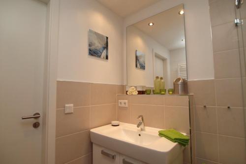 ein Bad mit einem Waschbecken und einem Spiegel in der Unterkunft Residenz von Flotow Wohnung 09 in Heiligendamm