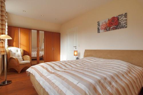 ein Schlafzimmer mit einem großen Bett und einem Stuhl in der Unterkunft Ferienhaus Nanni in Wittenbeck
