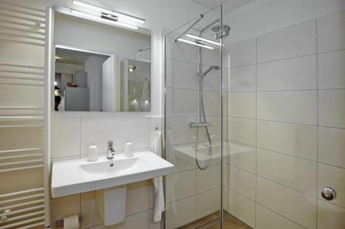 a white bathroom with a sink and a shower at Linden-Palais Wohnung 06 in Heiligendamm