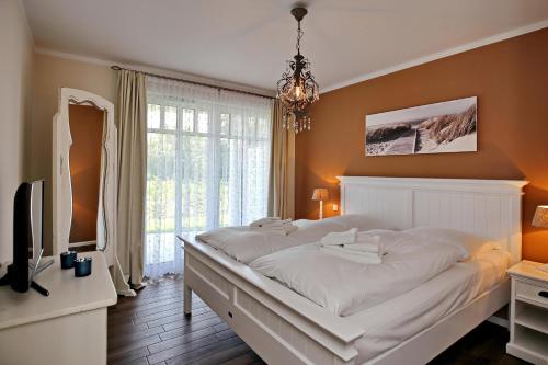 um quarto com uma grande cama branca e uma televisão em Linden-Palais Wohnung 03 em Heiligendamm