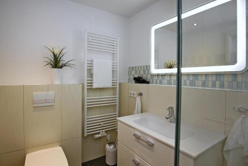 y baño con lavabo, aseo y espejo. en Linden-Palais Wohnung 18, en Heiligendamm