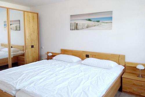 a bedroom with a large white bed and a mirror at Residenz von Flotow Wohnung 05 in Heiligendamm