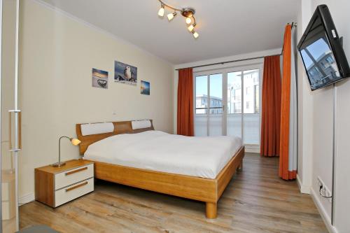 a bedroom with a bed and a television in it at Villa Strandvogt Wohnung 11 in Börgerende-Rethwisch