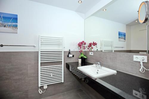 a bathroom with a sink and a mirror at Villa Strandvogt Wohnung 11 in Börgerende-Rethwisch