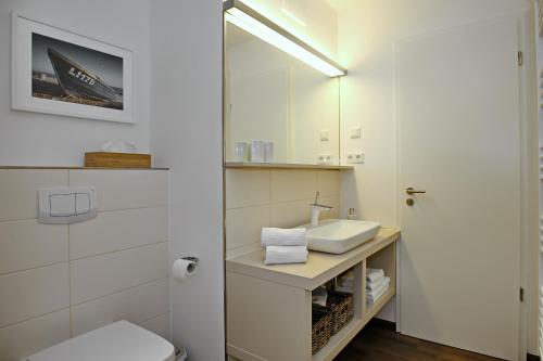 a bathroom with a sink and a toilet and a mirror at Linden-Palais Wohnung 26 in Heiligendamm