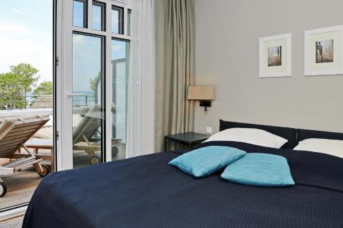 a bedroom with a bed with blue pillows and a balcony at Linden-Palais Wohnung 34 in Heiligendamm