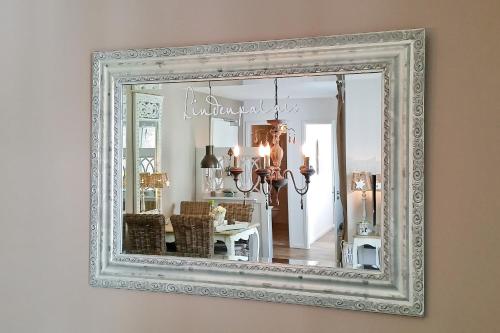 a mirror with a white frame hanging on a wall at Linden-Palais Wohnung 12 in Heiligendamm