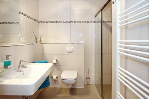 ein weißes Bad mit einem Waschbecken und einem WC in der Unterkunft Linden-Palais Wohnung 14 in Heiligendamm