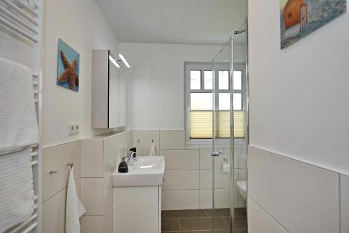 a white bathroom with a sink and a mirror at Linden-Palais Wohnung 13 in Heiligendamm