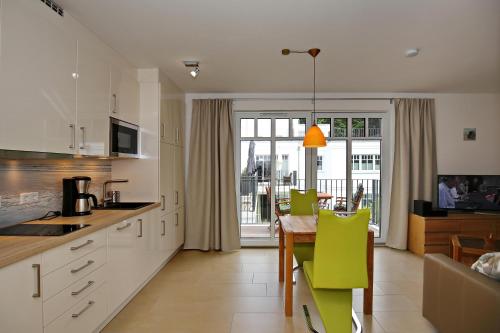 uma cozinha com uma mesa e cadeiras verdes em Linden-Palais Wohnung 27 em Heiligendamm