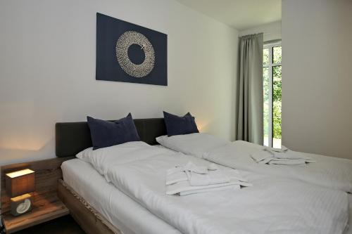 uma cama grande com lençóis brancos e almofadas azuis em Linden-Palais Wohnung 08 em Heiligendamm