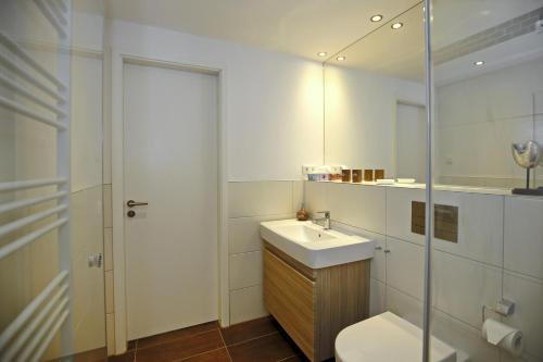 a bathroom with a sink and a toilet and a mirror at Linden-Palais Wohnung 08 in Heiligendamm
