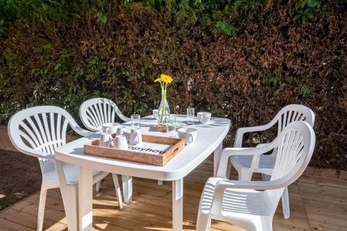 - une table blanche avec des chaises blanches et un plateau avec des fleurs dans l'établissement Le Cht'Agathois, à Agde