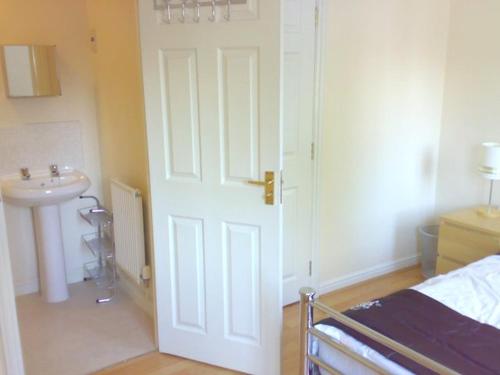 a bedroom with a bed and a sink and a door at Wigmore House in Great Barr