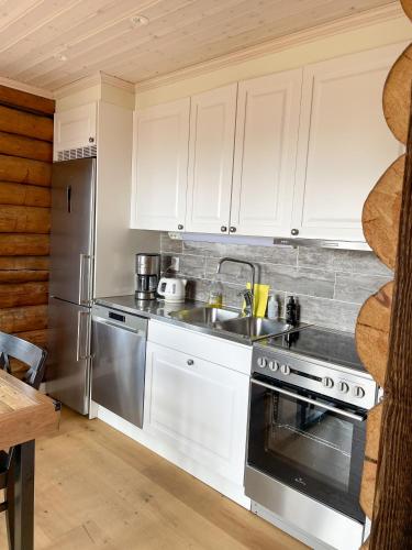a kitchen with white cabinets and a stainless steel stove at The Fryksås Chamber in Orsa