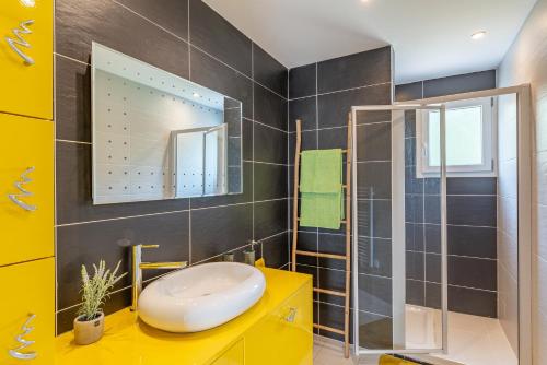 La salle de bains est pourvue d'un lavabo jaune et d'un miroir. dans l'établissement Paoli, à LʼÎle-Rousse