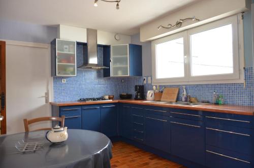 une cuisine avec des placards bleus, une table et une fenêtre dans l'établissement Maison Golfe du Morbihan - Vue Mer - Plage à 600m - 6 Chambres, à Séné