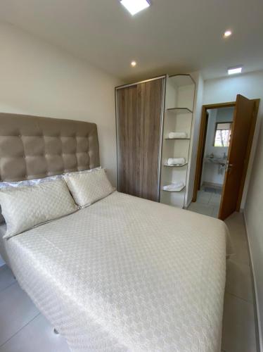 a bedroom with a large white bed and a bathroom at Aconchego Serra Imperial-101 in Petrópolis
