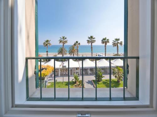 a window with a view of the beach and palm trees at Medusa Apartment - Lungomare in Finale Ligure