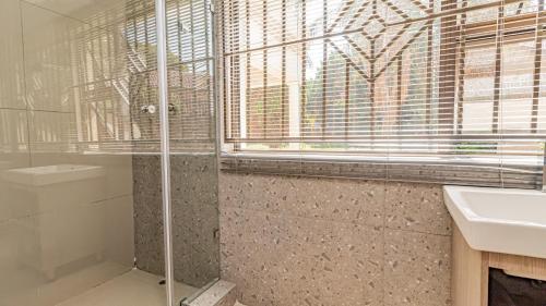 a bathroom with a shower and a sink and a window at See You There Accommodation 1 in Centurion