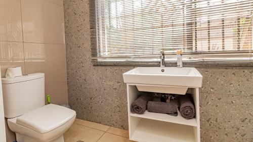 a bathroom with a white sink and a toilet at See You There Accommodation 1 in Centurion
