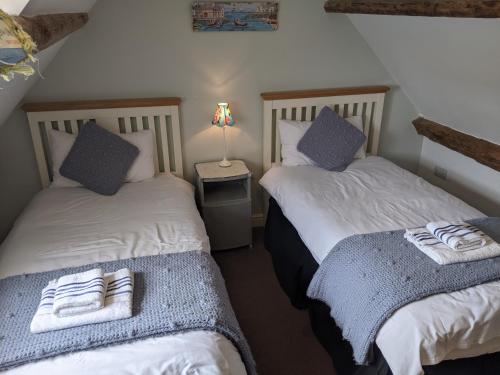 two twin beds in a room with a lamp at Whitby Sea View Cottage in Whitby