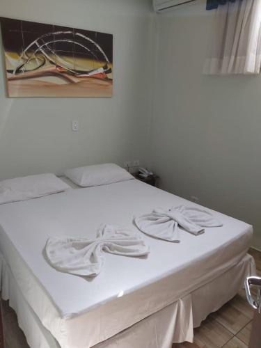 Una cama blanca con toallas blancas encima. en Hotel e Pousada Caroline, en Foz do Iguaçu