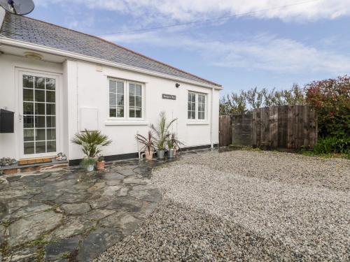 a white house with a fence and a gravel driveway at Badgers Way in Tintagel