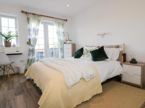 ein Schlafzimmer mit einem großen weißen Bett mit grünen Kissen in der Unterkunft Badgers Way in Tintagel