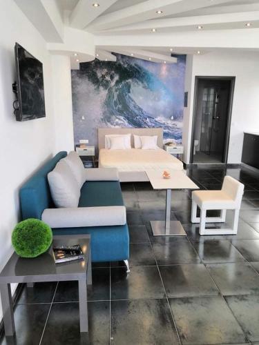 a living room with a blue couch and a bed at Hotel George suite 1 in Limenas
