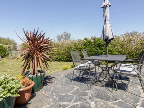 a patio with a table and chairs and an umbrella at Badgers Way in Tintagel