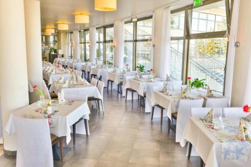 une rangée de tables dans un restaurant avec des tables et des chaises blanches dans l'établissement Sanatorium Uzdrowiskowe Bałtyk, à Kołobrzeg