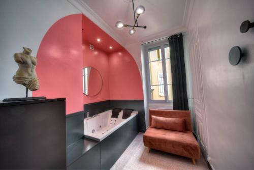La salle de bains est pourvue d'un mur rouge avec une chaise et un lavabo. dans l'établissement La Suite en Rose - Spa - Brotteaux, à Lyon