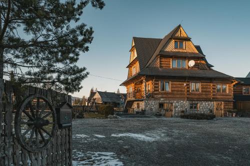 a large wooden house with a wooden wheel in front of it at Apartamenty Truchanówka przy Dolinie Chochołowskiej in Witów