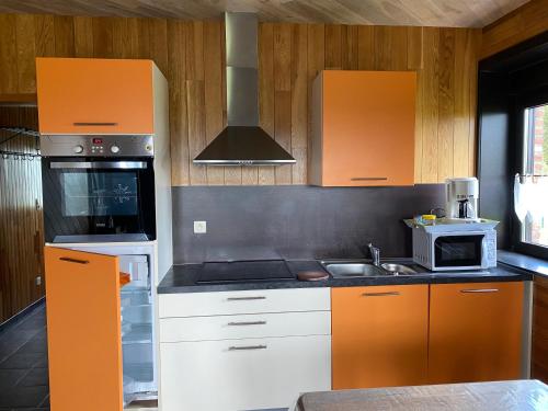 - une cuisine avec des placards orange et blancs et un évier dans l'établissement L'évasion du berger australien, à Couvin