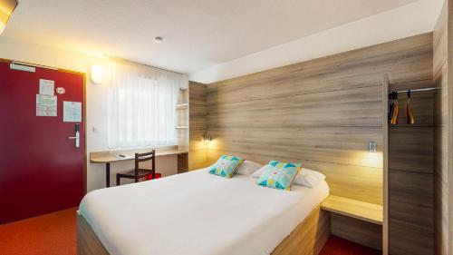 a bedroom with a white bed and a wooden wall at Ever Route 64 Brit Hotel Tarbes Ibos in Tarbes