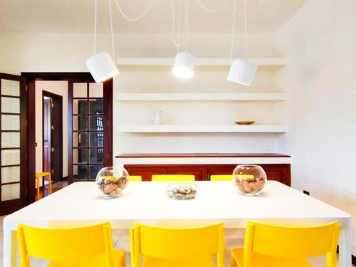 a dining room with a white table and yellow chairs at Vivienda Vacacional Villa El Mirador in San Sebastián de la Gomera