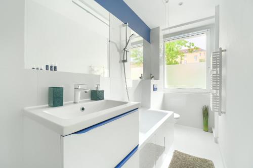 baño blanco con lavabo y ventana en Apartament Jazz, en Szczecin