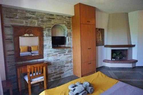 1 dormitorio con pared de piedra, cama y chimenea en Artemisia House, en Tsagkarada