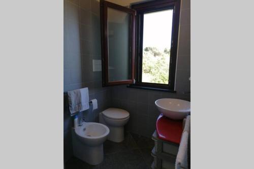 a bathroom with a sink and a toilet and a window at Open Space a due passi dal mare in Ustica