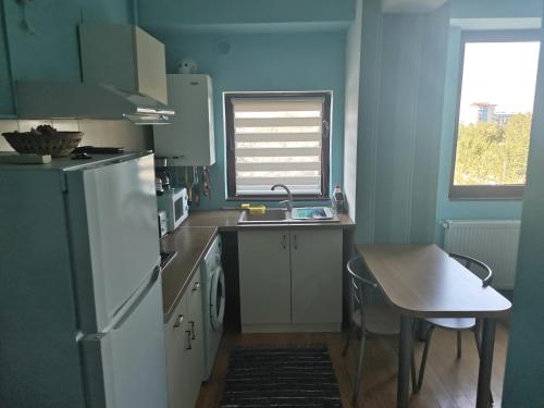 a kitchen with a refrigerator and a table and a window at Apartament Select Mamaia in Mamaia