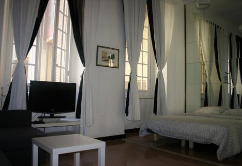 sala de estar con TV, cama y ventanas en The Gate To Cinque Terre, en La Spezia